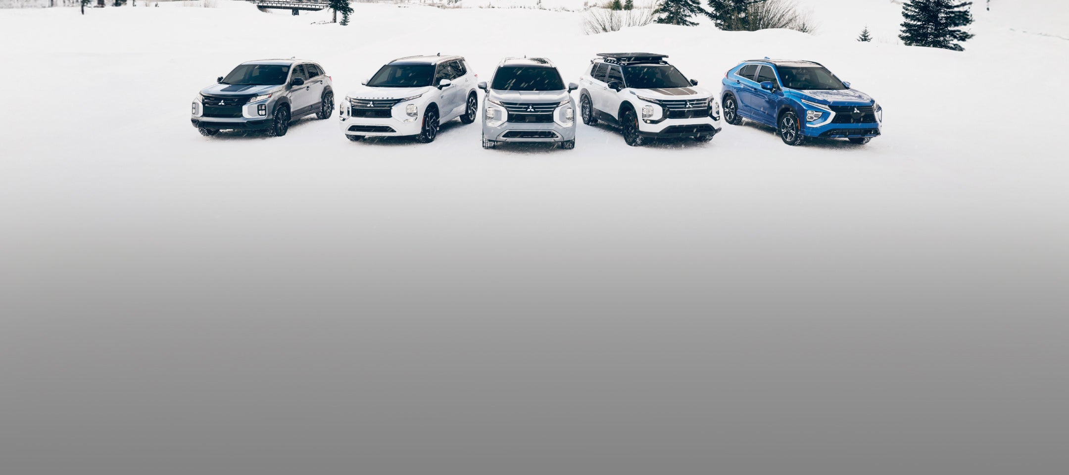 A lineup of Mitsubishi SUVs in the snow