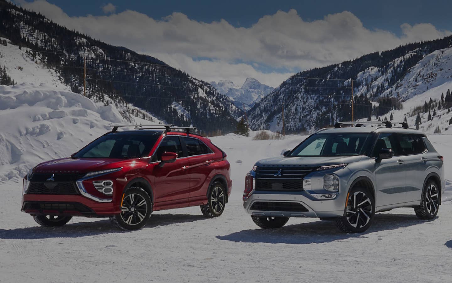 A red Mitsubishi Eclipse Cross compact SUV and silver Mitsubishi Outlander SUV with AWD and 4WD in the snow