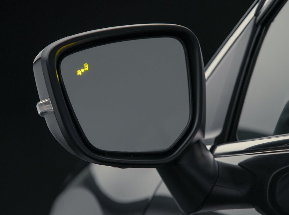 Close up of side mirror of black 2023 / 2024 Mitsubishi Eclipse Cross Compact SUV with Blind Spot Warning Light illuminated