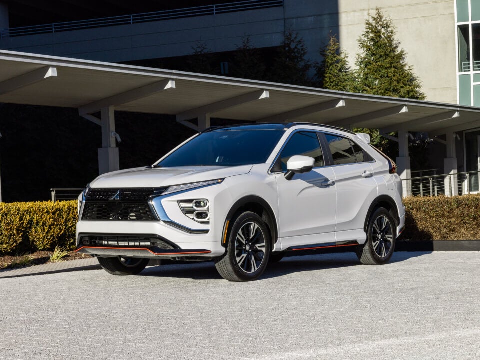 Angled front view of white 2023 / 2024 Mitsubishi Eclipse Cross Compact SUV parked in front of house 
