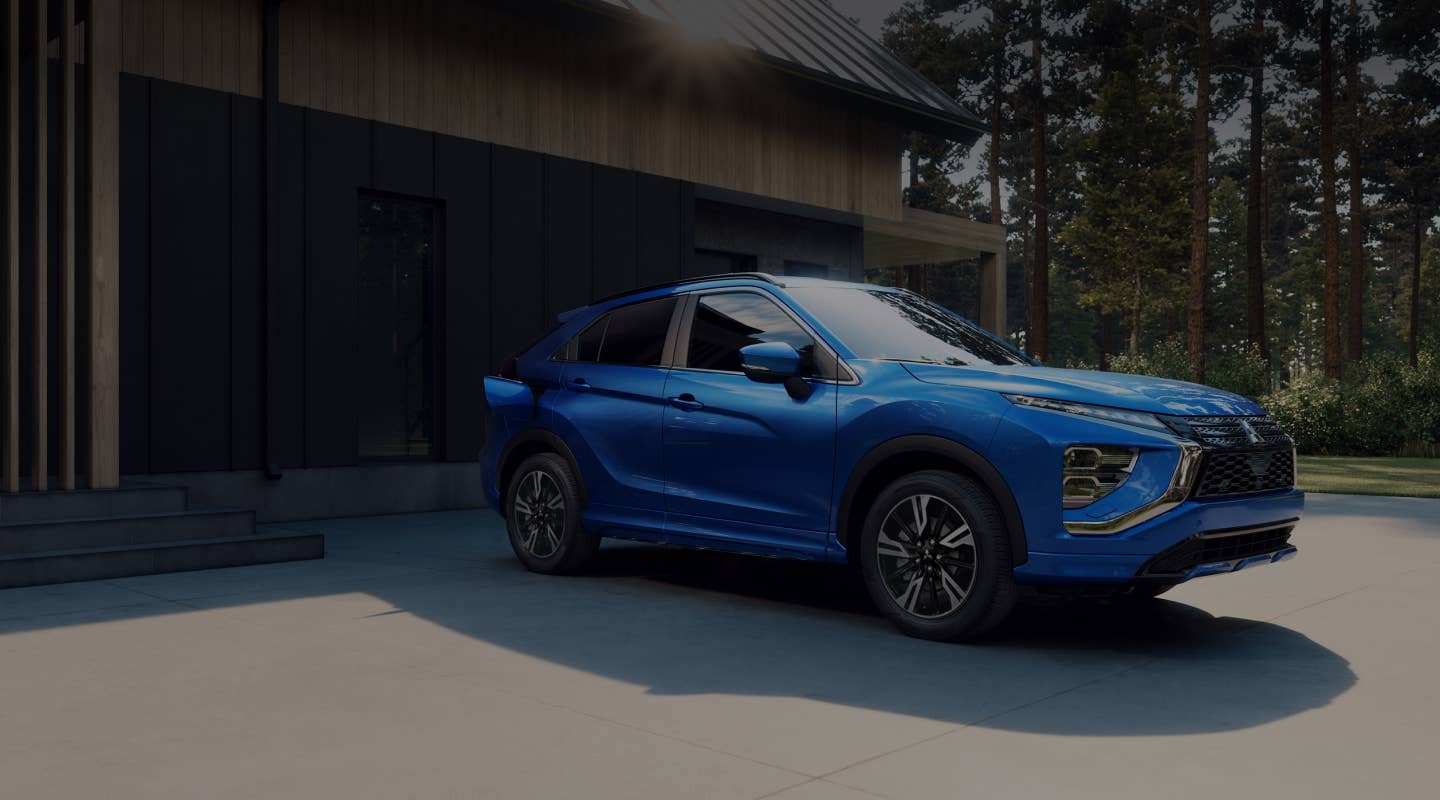 A blue 2024 / 2025 Mitsubishi Eclipse Cross Compact SUV parked in front of a house