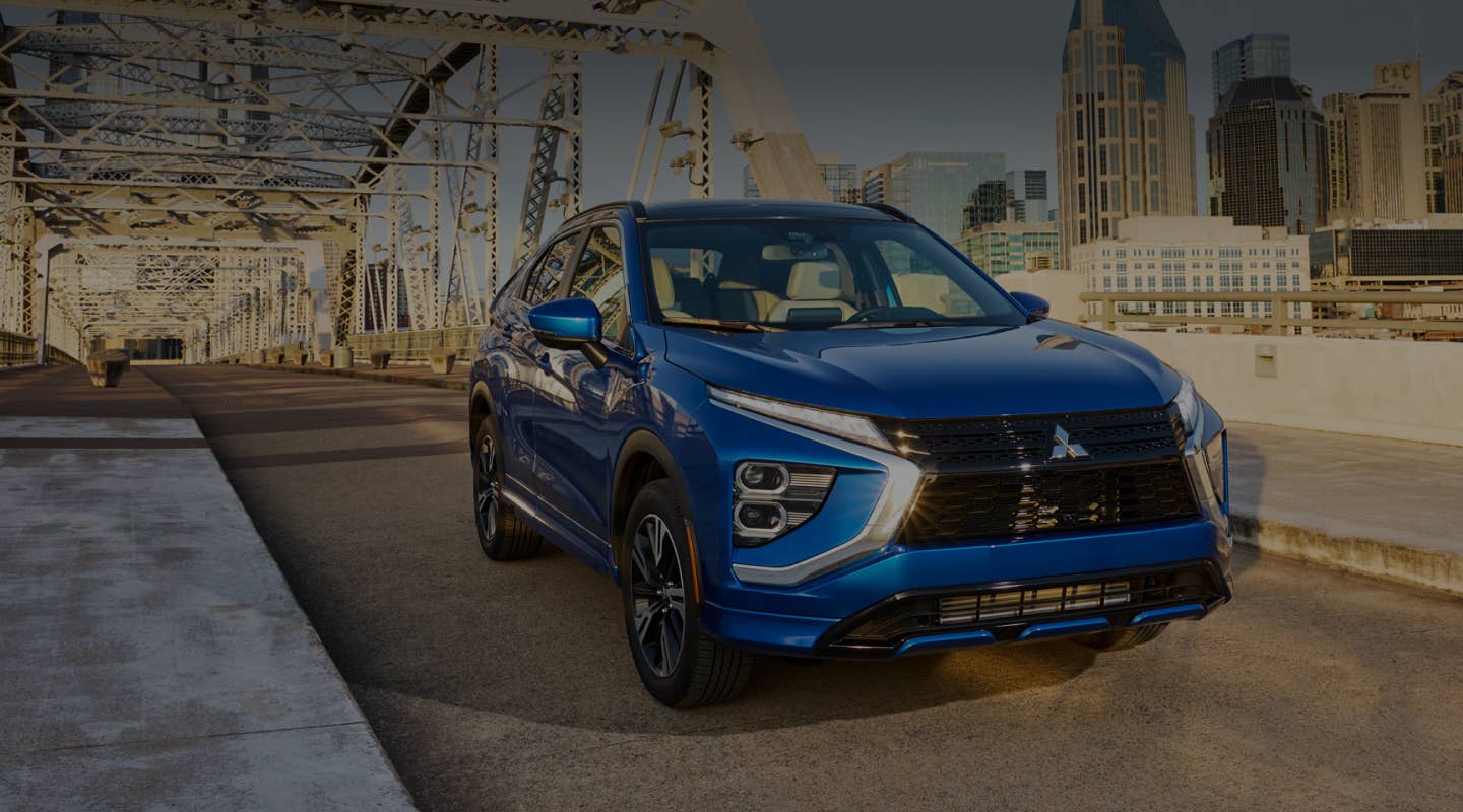 A blue 2025 Mitsubishi Eclipse Cross Compact SUV driving on a bridge