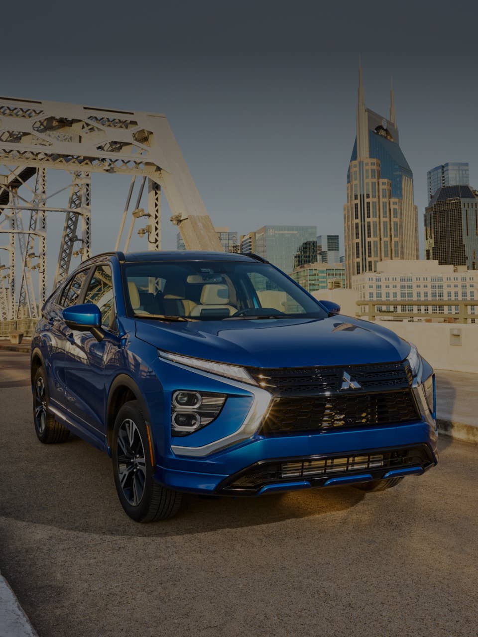A blue 2025 Mitsubishi Eclipse Cross Compact SUV driving on a bridge