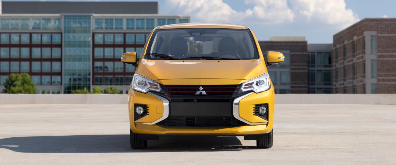 Front profile of a sand yellow metallic 2022 Mitsubishi Mirage parked in a parking lot