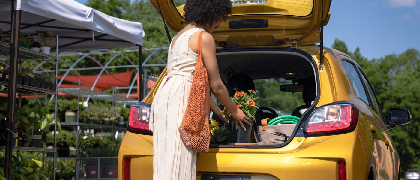 Woman placing flower pot and other items in the spacious cargo area in the 2022 Mitsubishi Mirage