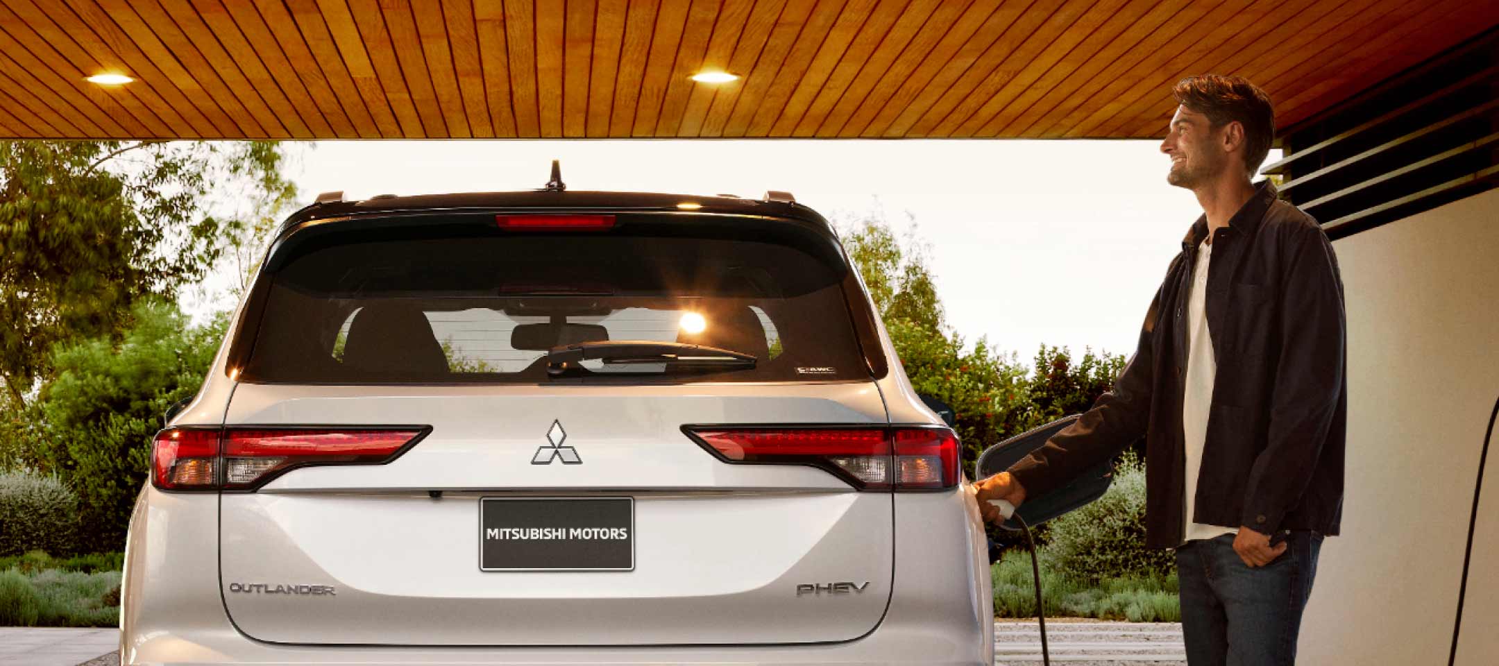 A man adding gas into a white 2023 Mitsubishi Outlander PHEV plug in hybrid