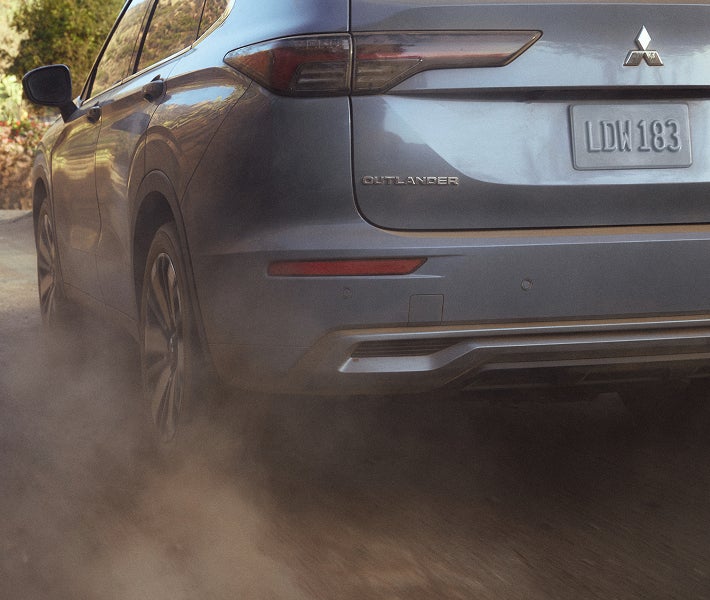 Close up on the wheels of a 2026 Mitsubishi Outlander PHEV SUV regenerative breaking and kicking up dust