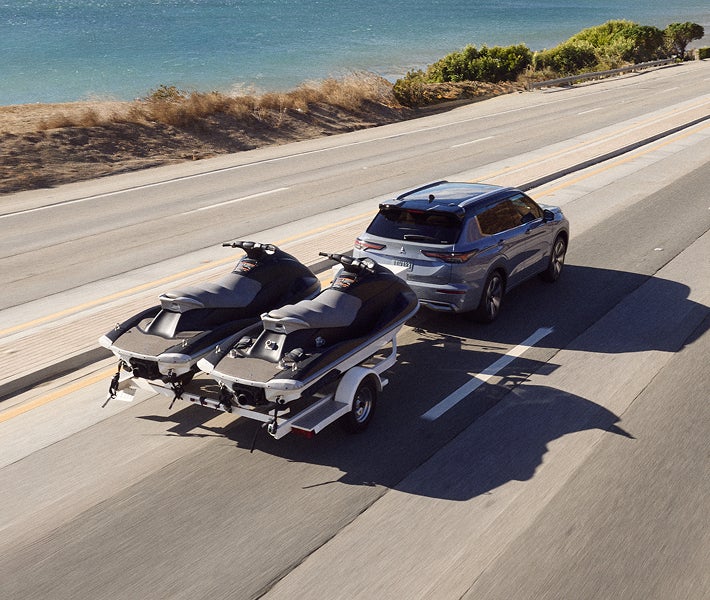 2026 Mitsubishi Outlander PHEV SUV showing off towing capacity by towing jet skis