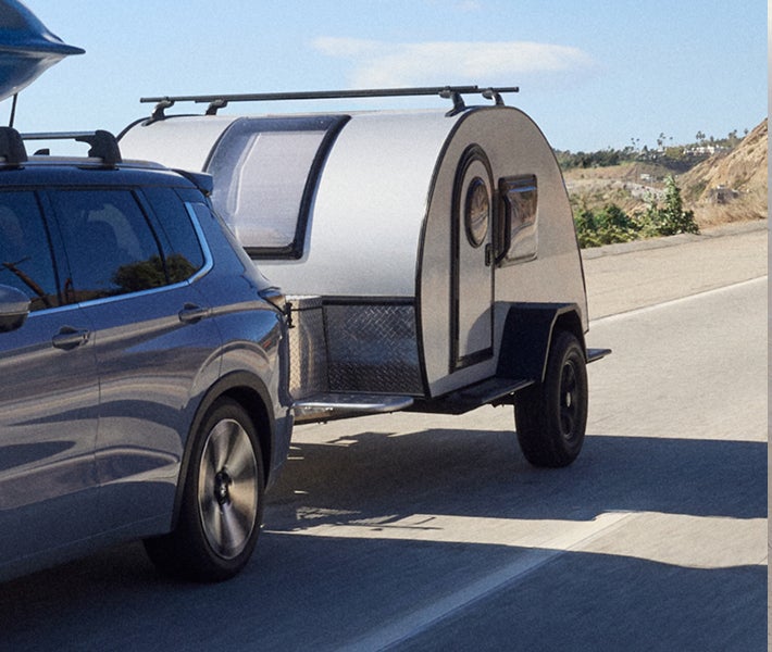2026 Mitsubishi Outlander PHEV SUV showing off towing capacity by towing a trailer