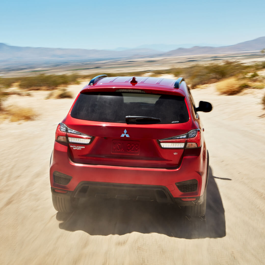 Back view of a red 2023 Mitsubishi Outlander Sport SUV driving in the desert