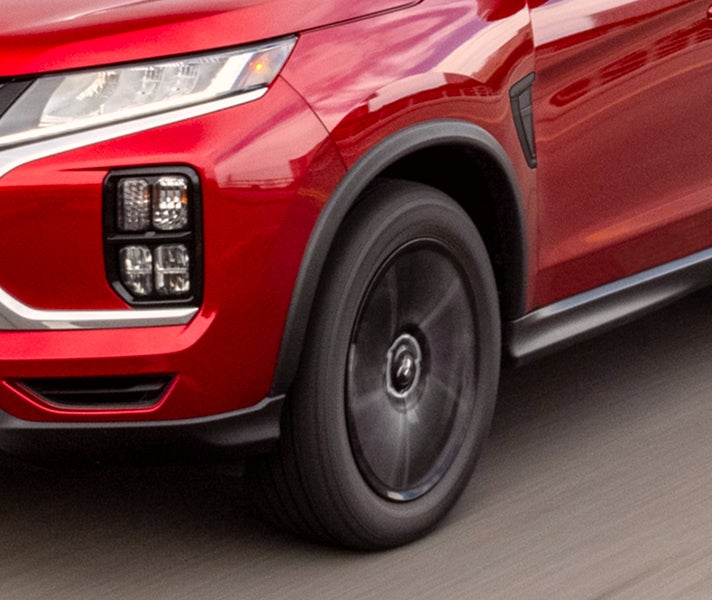 Close up angled view of red 2026 Mitsubishi Outlander Sport SUV with black rim tires 
