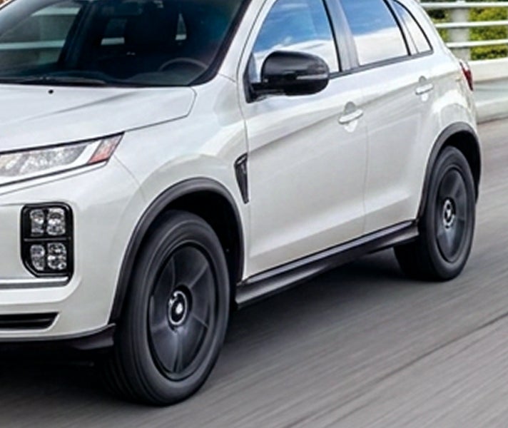 Close up angled view of white 2026 Mitsubishi Outlander Sport SUV with black rim tires