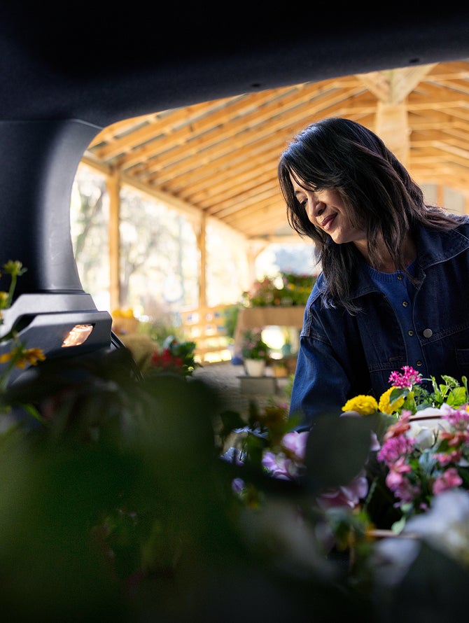 Person loading flowers in the versatile and flexible cargo area in the 2027 Mitsubishi Outlander Sport