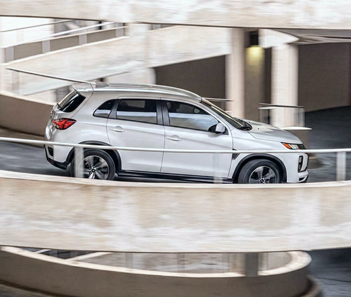 White 2027 Mitsubishi Outlander Sport driving down a ramp showing the available super all wheel control