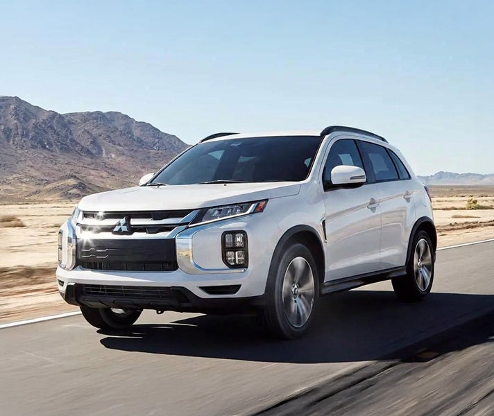2027 Mitsubishi Outlander Sport driving on a desert road with a mountain in the background