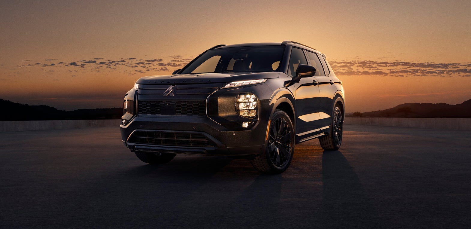 Mitsubishi Outlander Black Edition at a still angle with an orange sunset in the background.