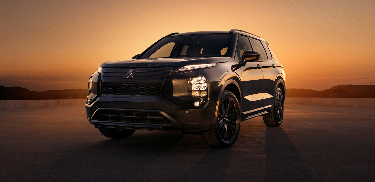 Mitsubishi Outlander Black Edition at a still angle with an orange sunset in the background.