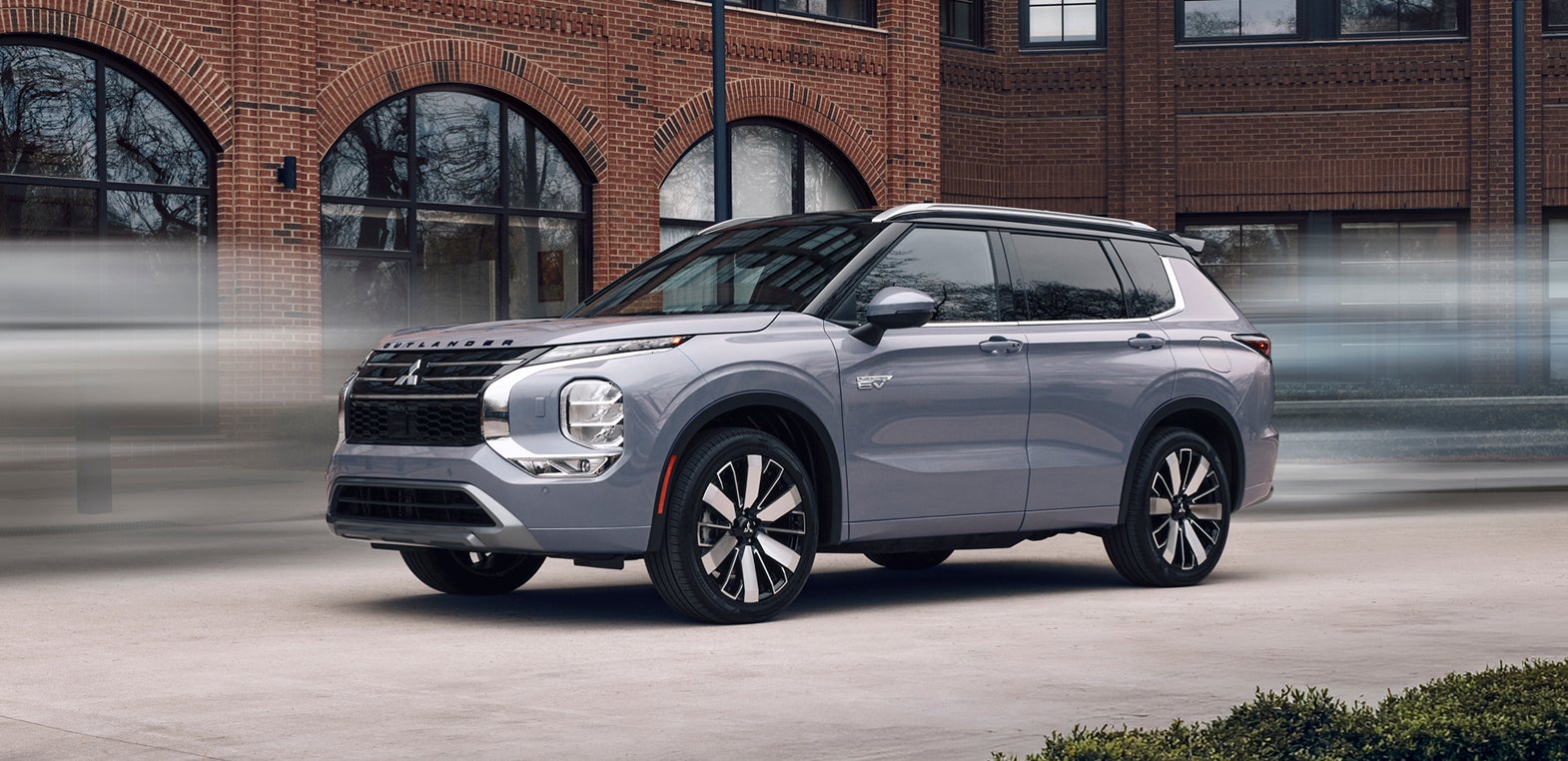 2026 Mitsubishi Outlander PHEV SUV stopped in front of a brick building.