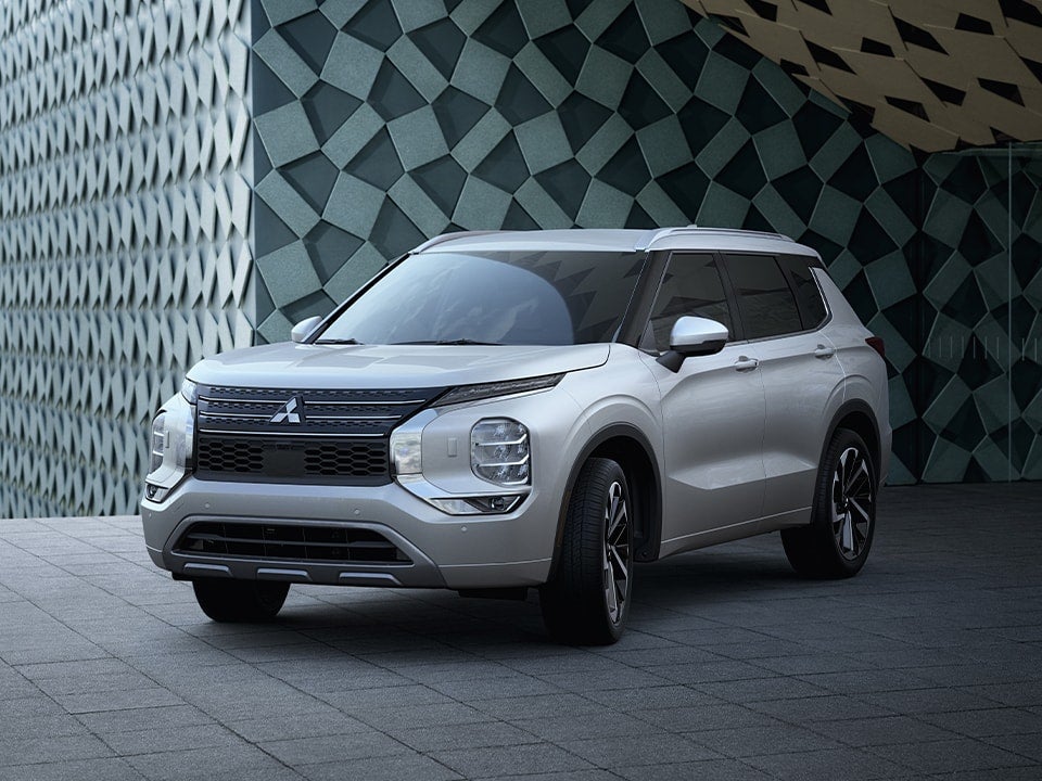 Side and front view of a parked 2023 Mitsubishi Outlander SUV driving fast on the road