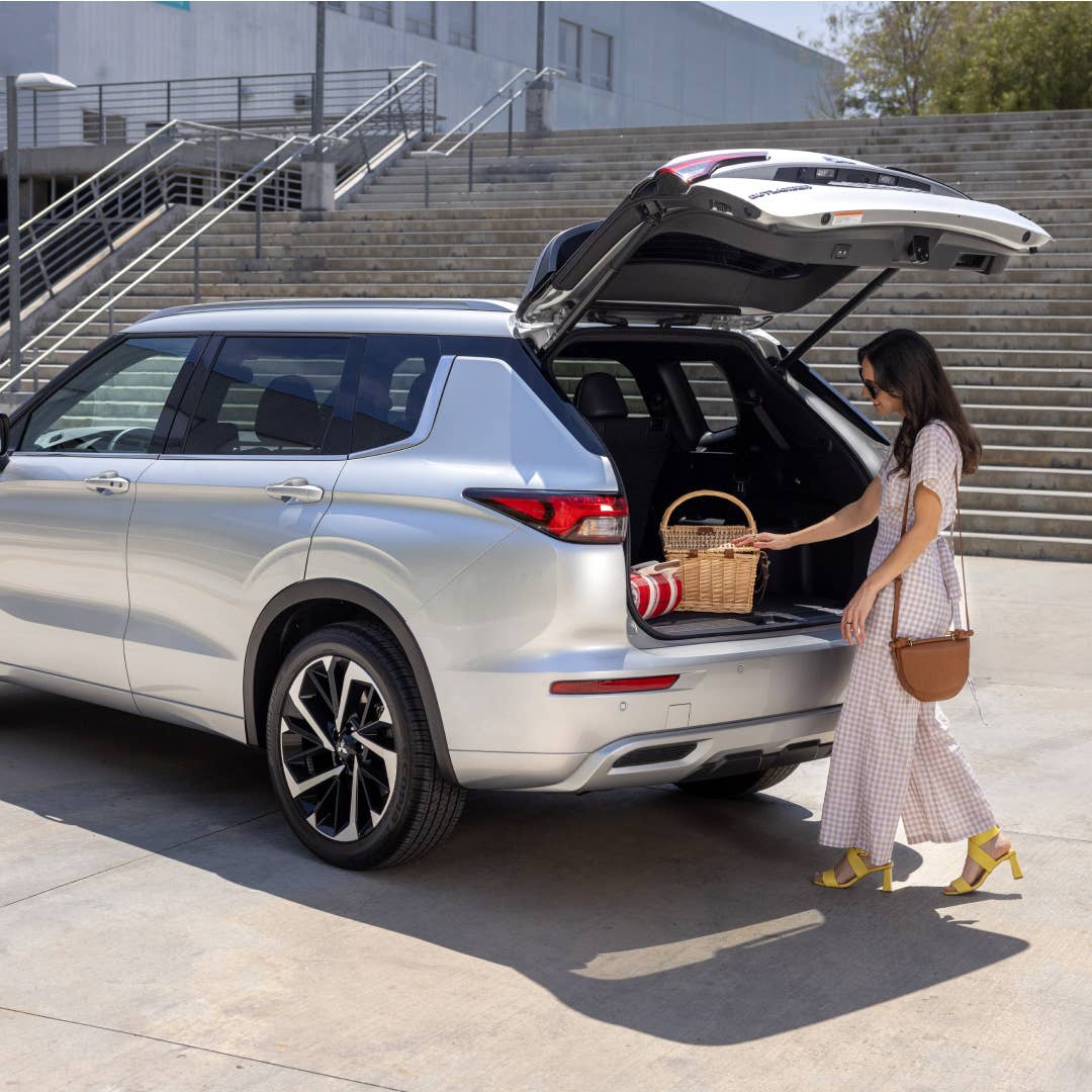 A woman putting things in the cargo space of a silver 2023 Mitsubishi Outlander SUV