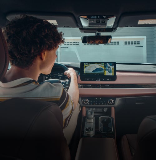 Person reversing out of a driveway in the 2026 Mitsubishi Outlander SUV using the multi view camera system