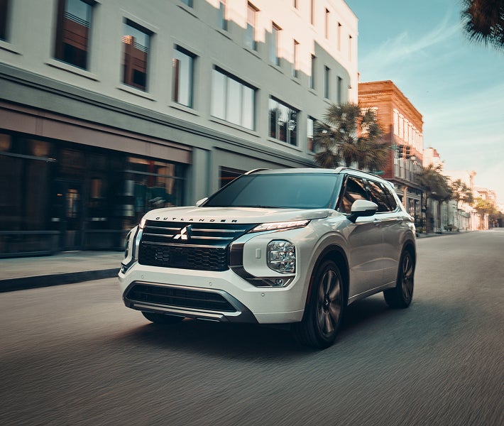 2026 Mitsubishi Outlander SUV driving on a city street showing off the MI Pilot Assist features