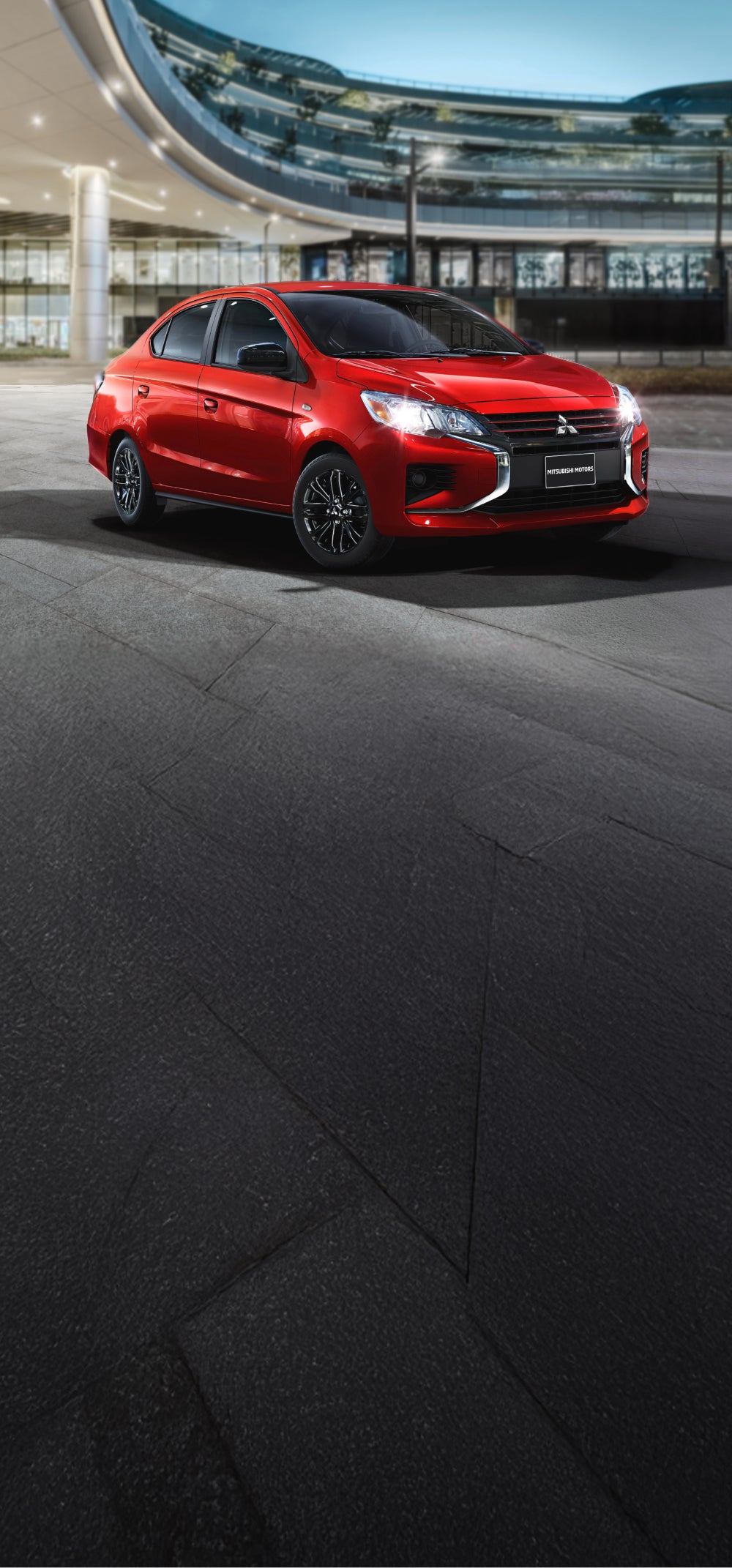 A red Mitsubishi Mirage G4 parked in front of a glass building. 