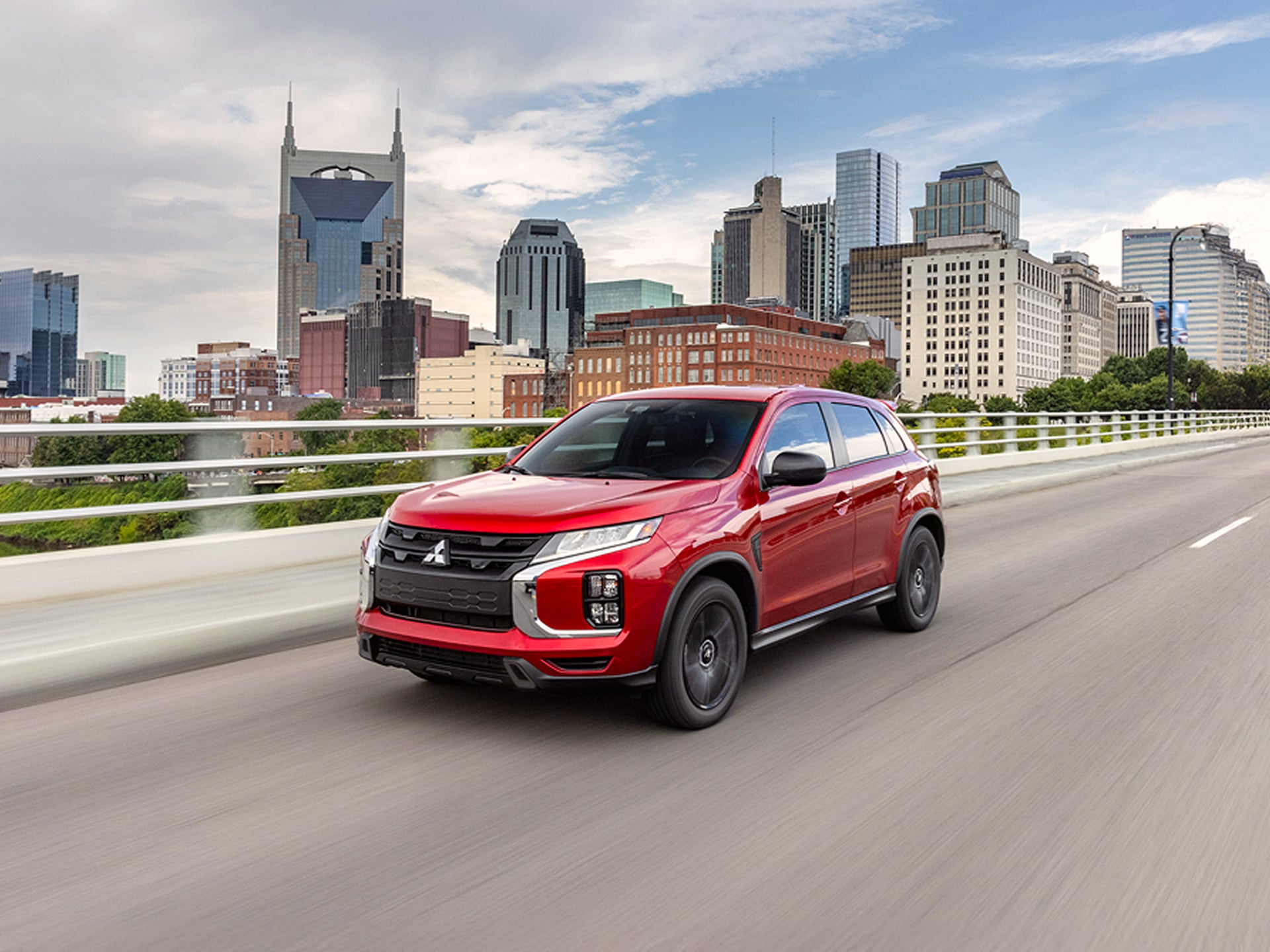 A red 2026 Mitsubishi Outlander Sport driving on a road in Nashville