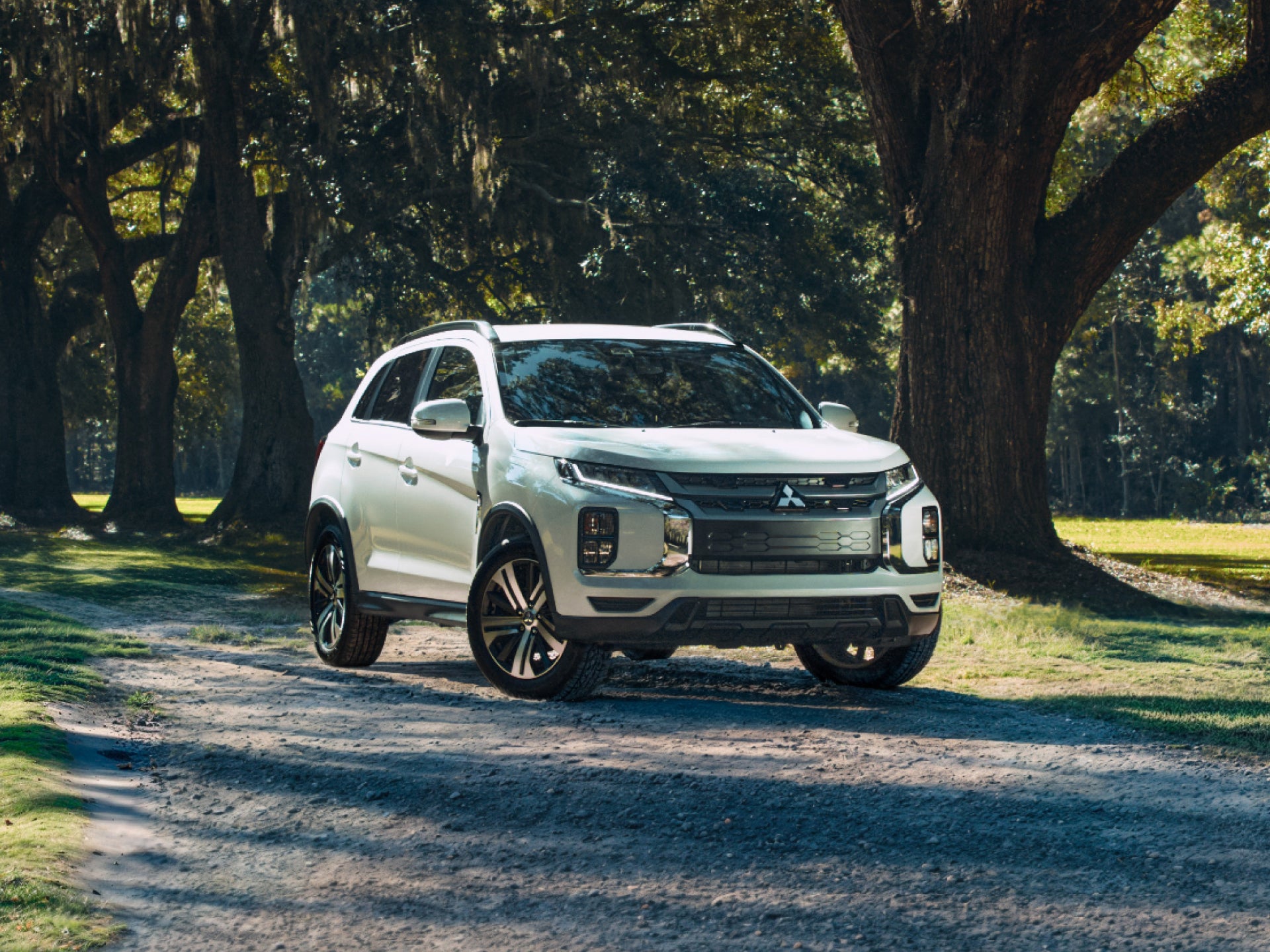 Mitsubishi Outlander Sport compact SUV parked on a dirt road under trees.